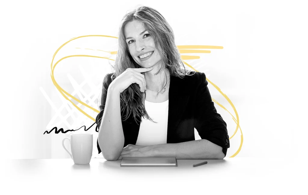 Ivana Srezović sitting at a table with a cup of coffee, smiling at the camera.